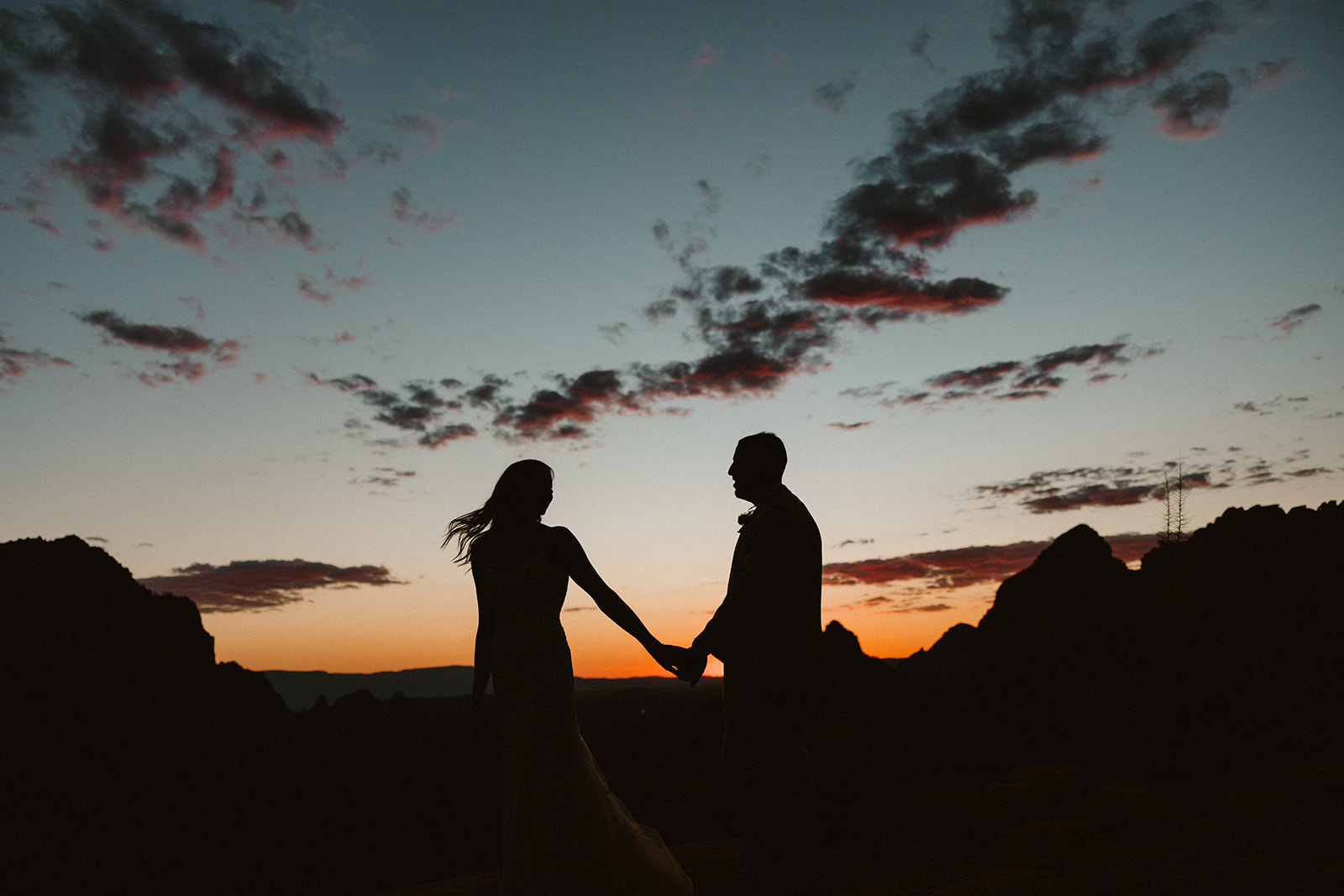 Silhouetted elopement couple holding hands at sunset in Sedona, a quiet moment full of emotion after deciding how to tell your family you're eloping.
