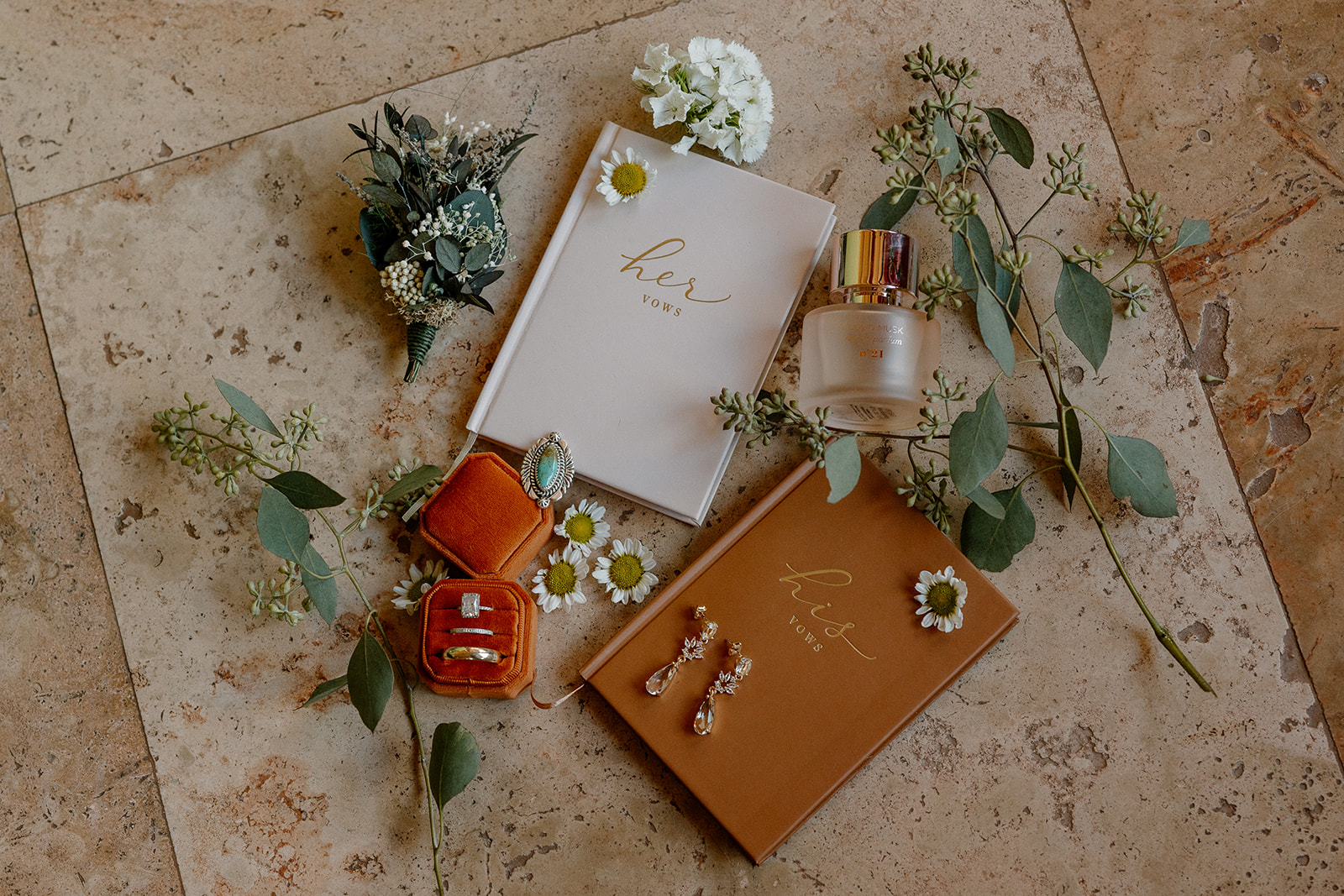 Bride and groom vow books on ground with flowers and greenery around 