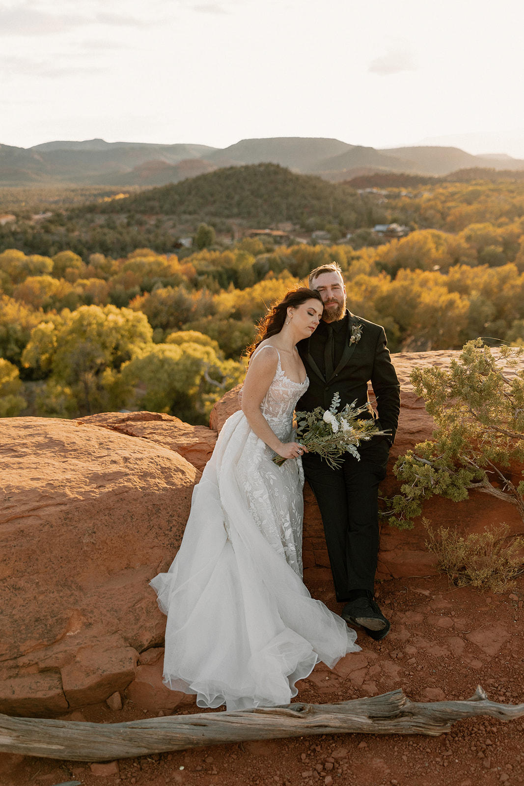 Couple sitting on red rocks in wedding attire after Arizona adventure elopement