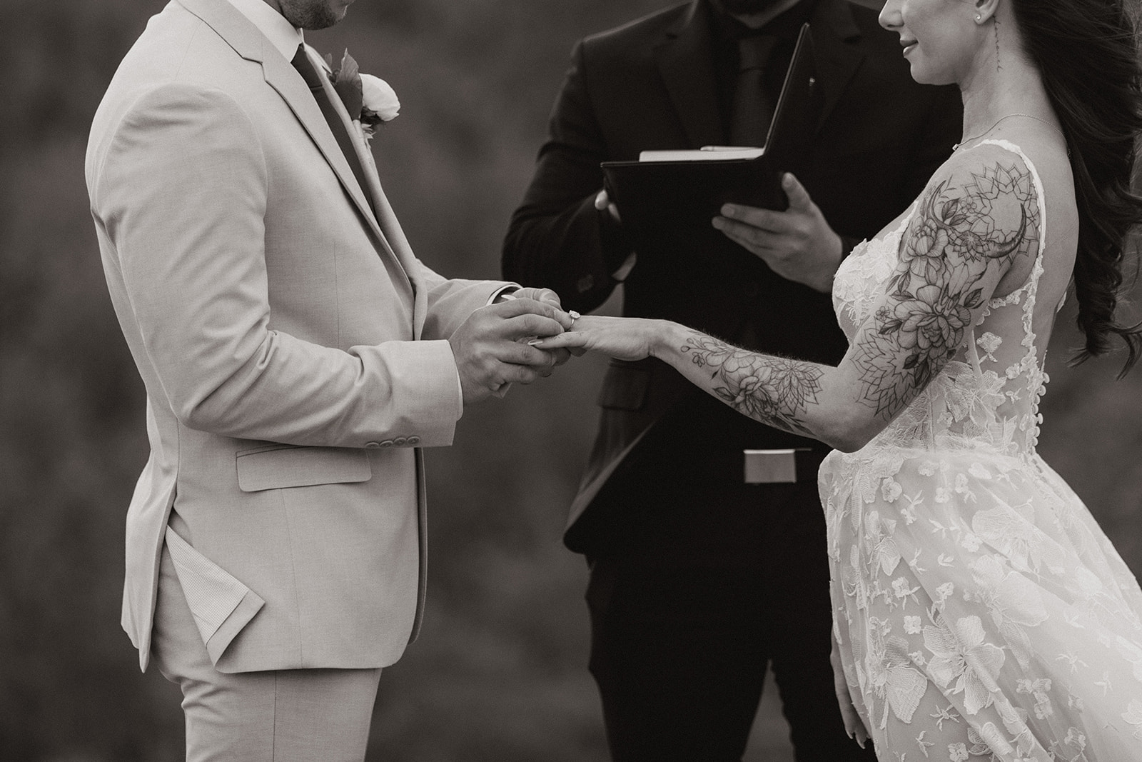 Close up of bride and groom with groom placing ring on bride's finger during intimate ceremony