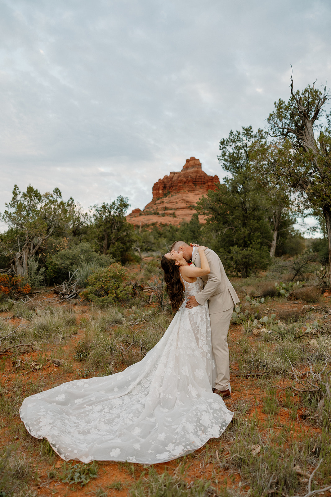 Groom kissing bride's neck while bride laughs during outdoor bridal portraits in Arizona