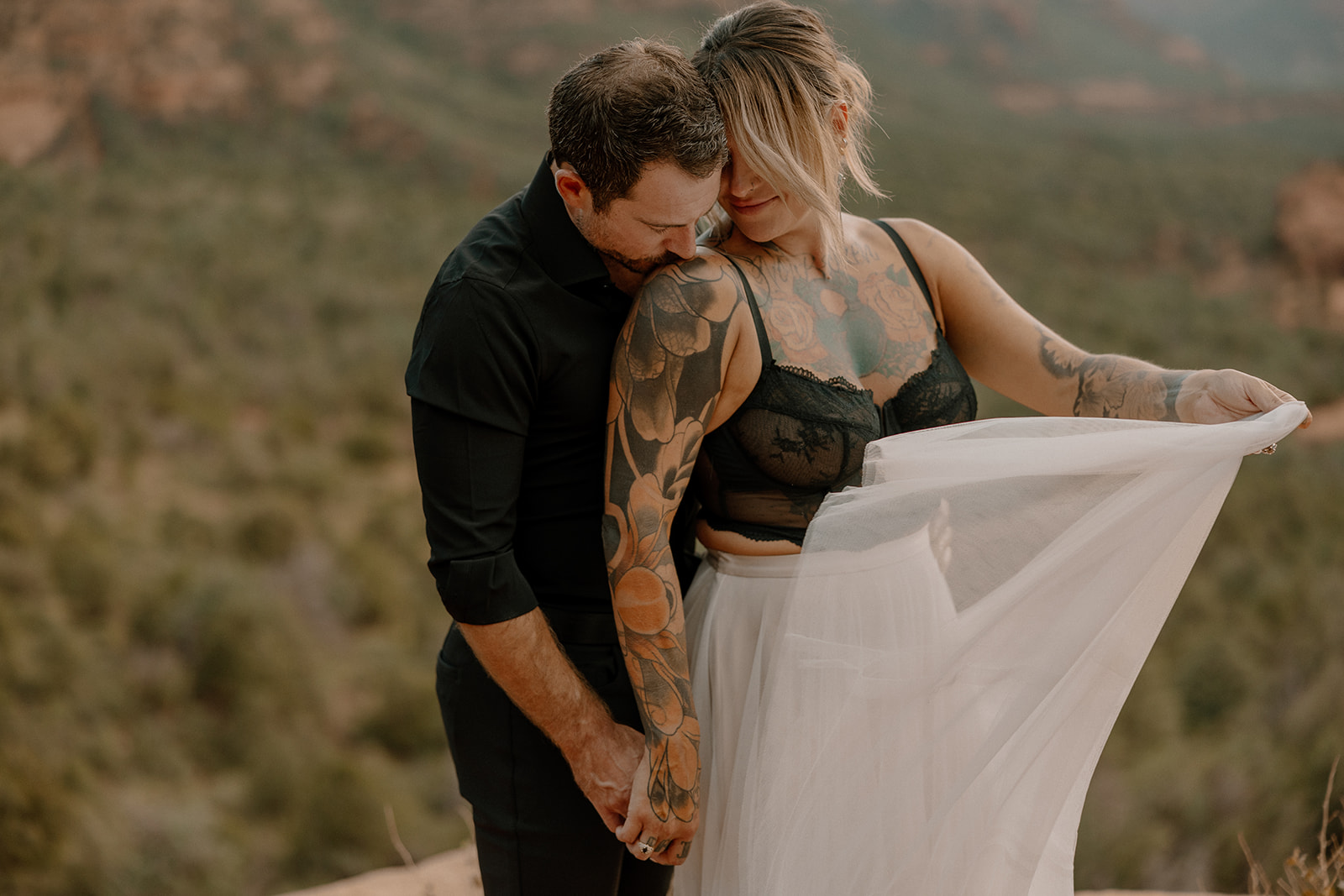 Bride in a sheer tulle skirt and black lace top holding hands with groom during an adventurous elopement

