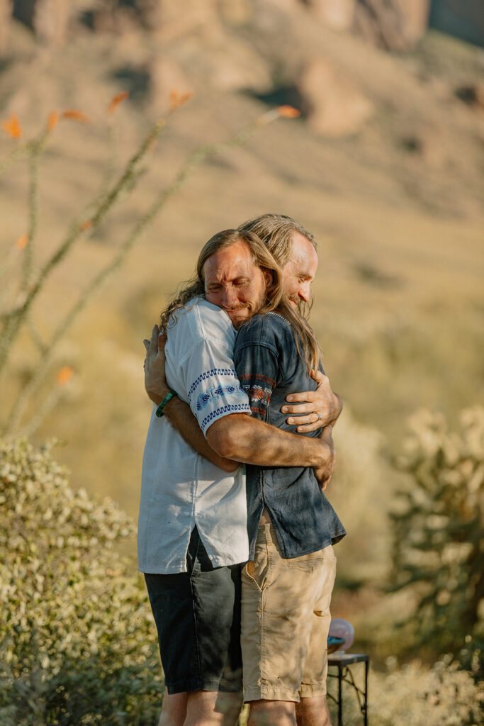 Two grooms hugging in celebration of their recent Arizona elopement in unique and personal wedding attire