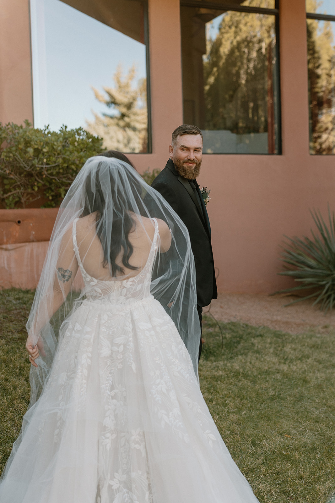 Bride in lace elopement dress with veil walking toward groom during first look.