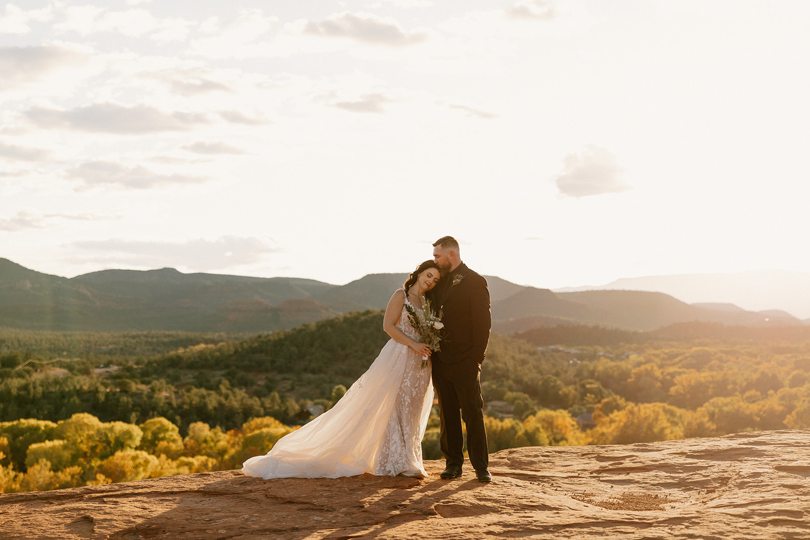 Newly married couple cuddle into one another at sunset after private elopement ceremony in Sedona proving what time is the best time to elope with the incredible light