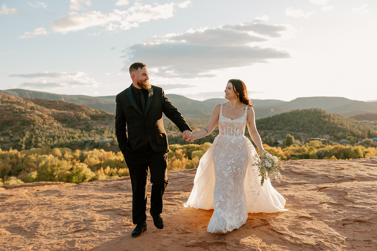 Bride and groom in elopement attire walking hand in hand laughing together