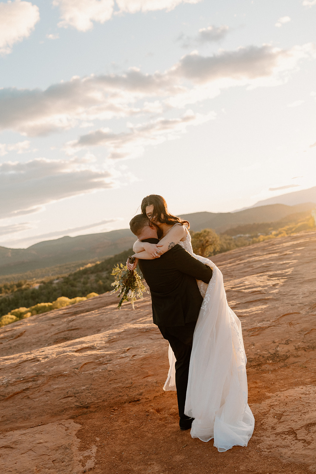 Groom lifts bride in air during golden hour photos celebrating recent marriage
