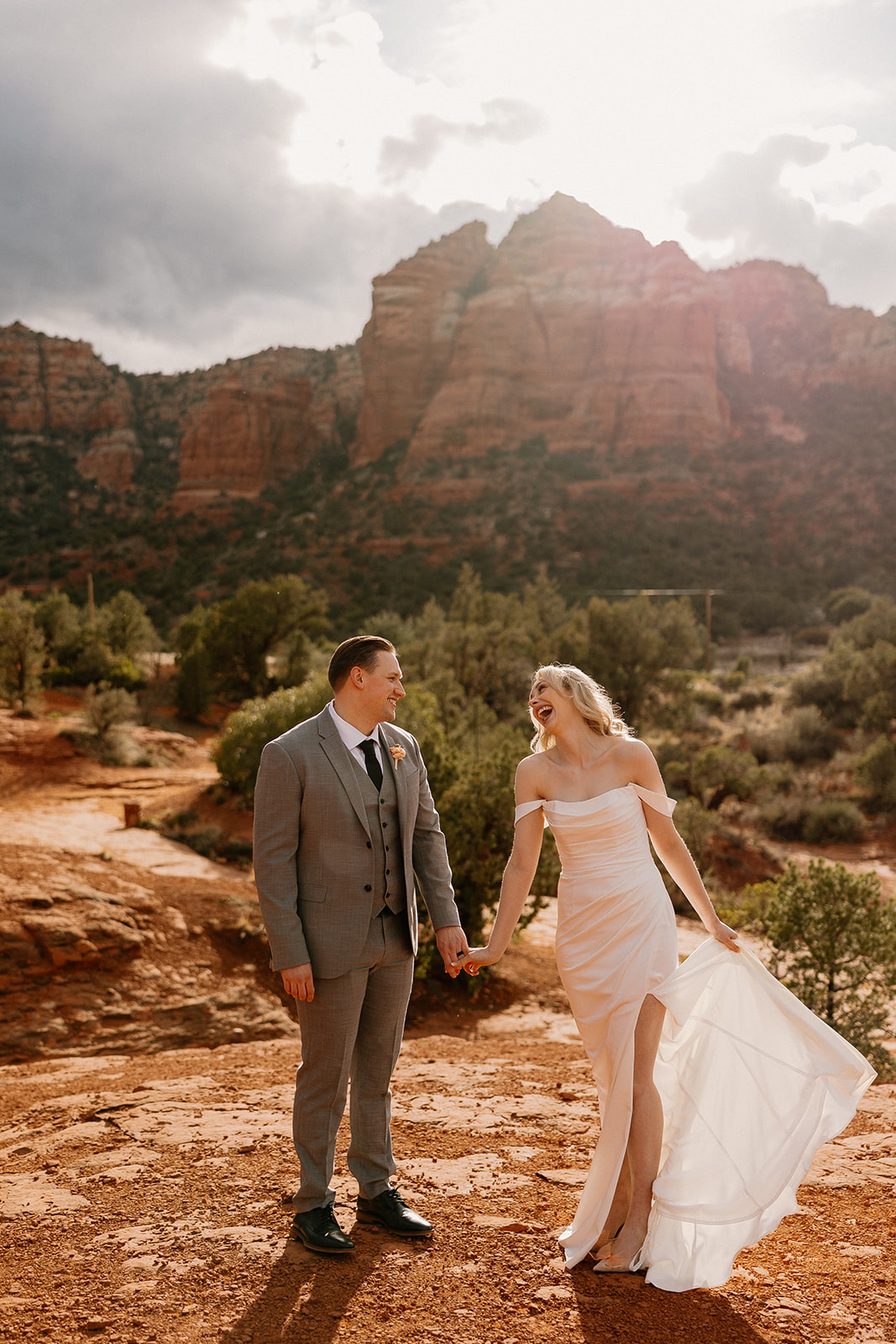 Couple holding hands at golden hour in Sedona, their laughter echoing through the desert as the sun breaks through the clouds—what is the best time of day to elope? This moment might be it.