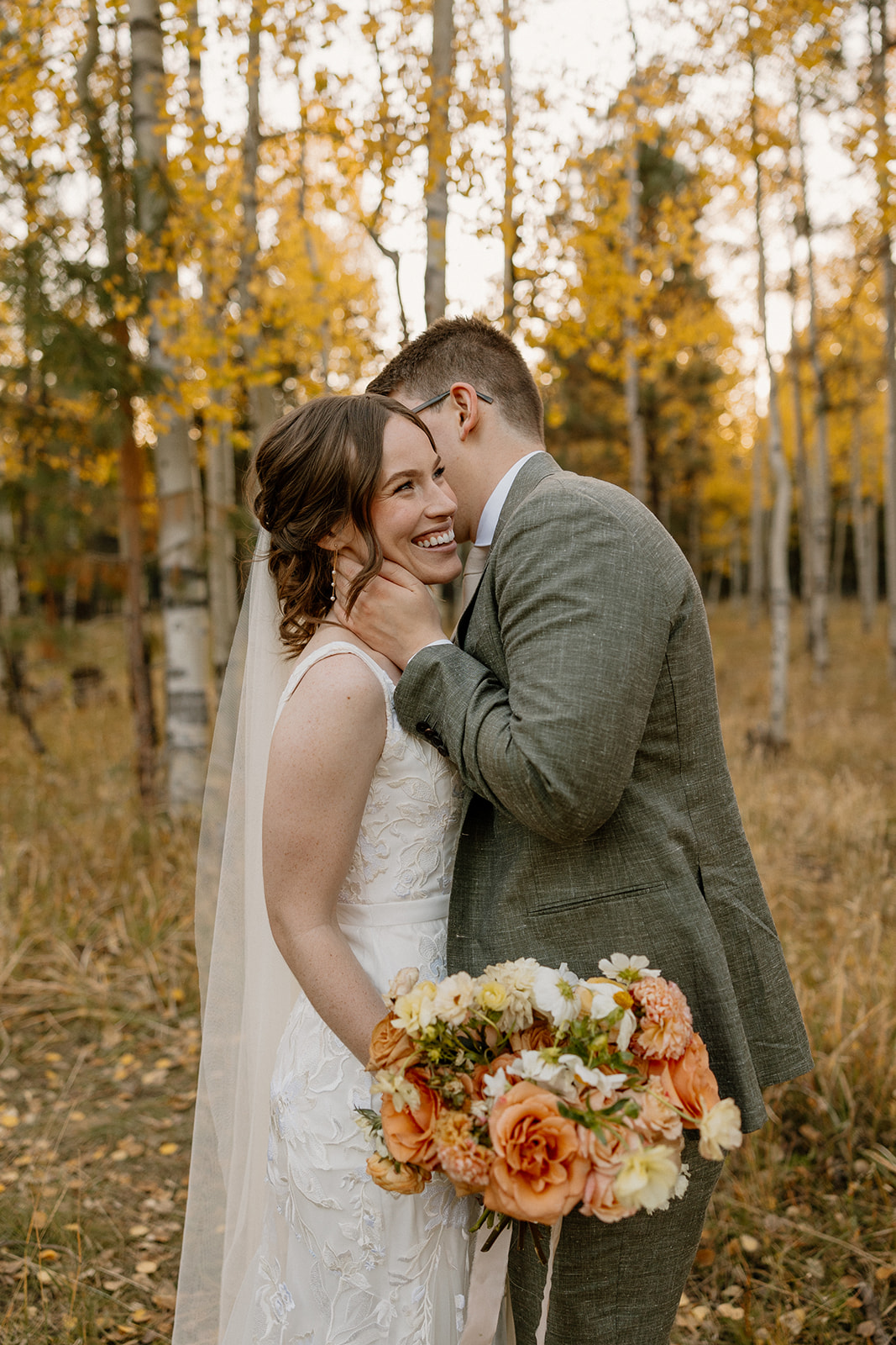 Groom with hand on bride's neck whispering in her ear a cheeky secret after forest elopement in Arizona