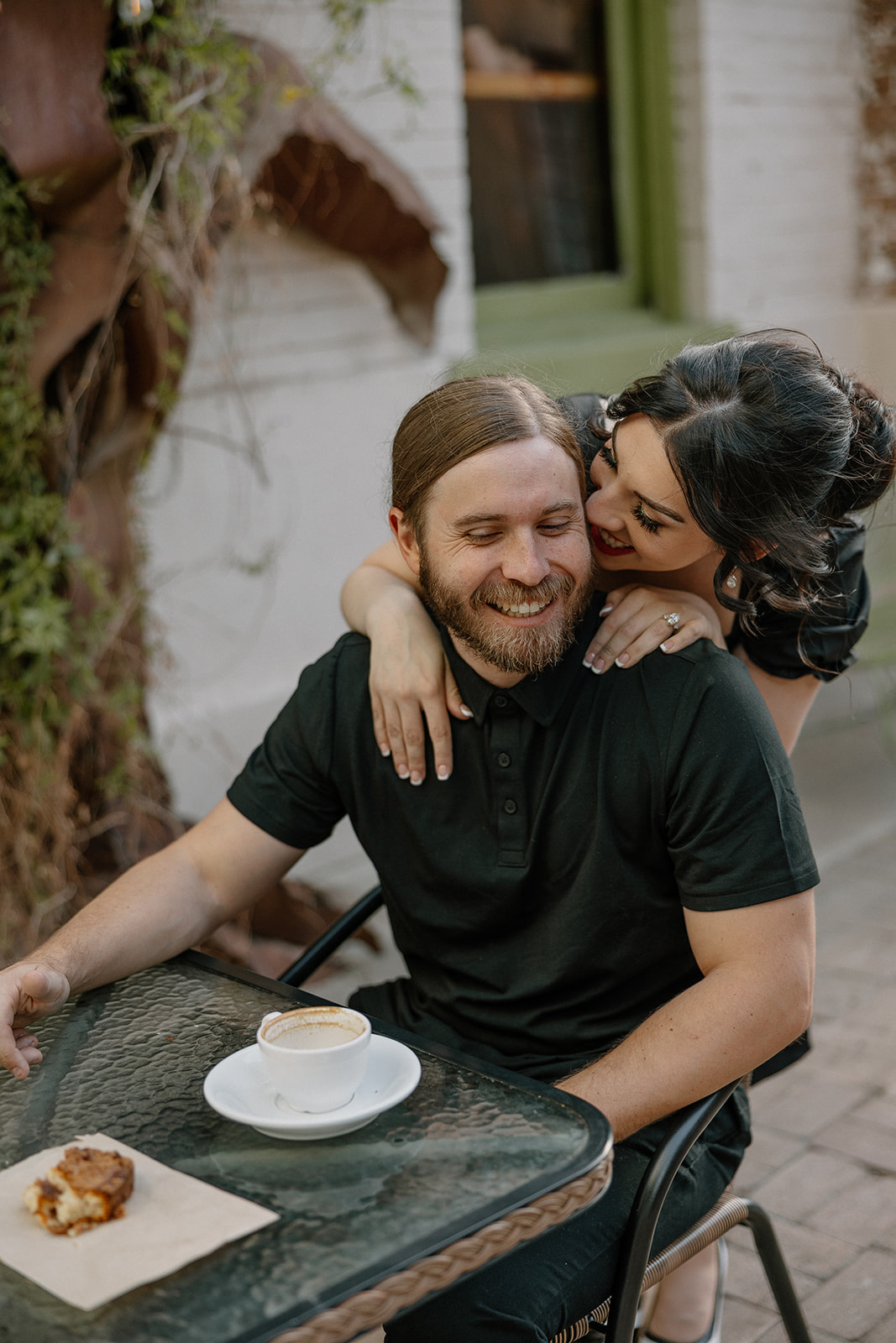 Woman leaning over man's shoulder and whispering in his ear during unique engagement photo ideas 