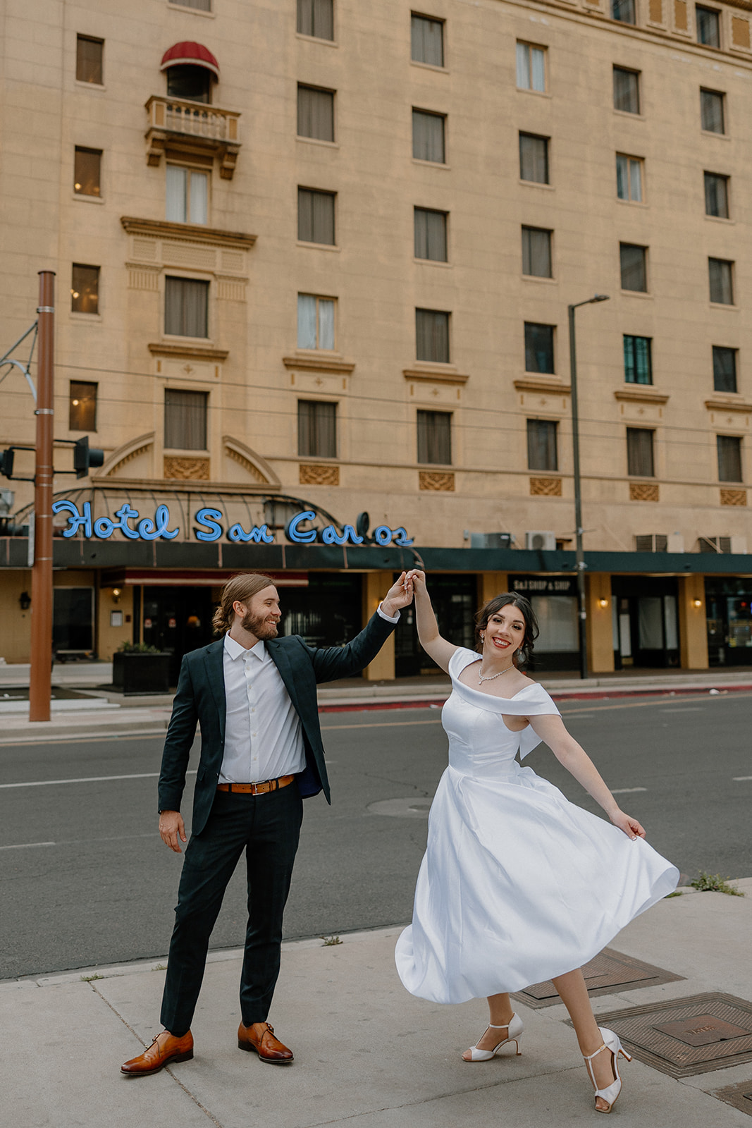 Couple dancing on the sidewalk in front of the vintage Hotel San Carlos sign — a fun and stylish city engagement moment.