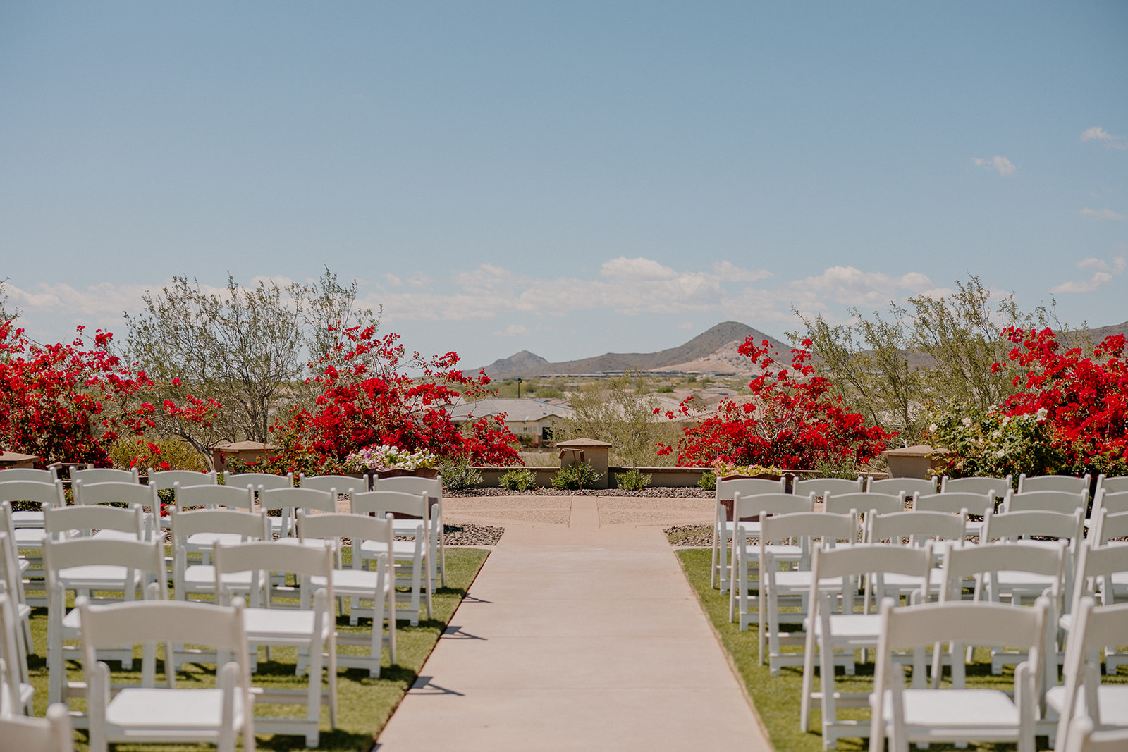 Stunning outdoor ceremony setup at Blackstone Country Club, lined with white chairs and framed by desert mountains and vibrant bougainvillea.