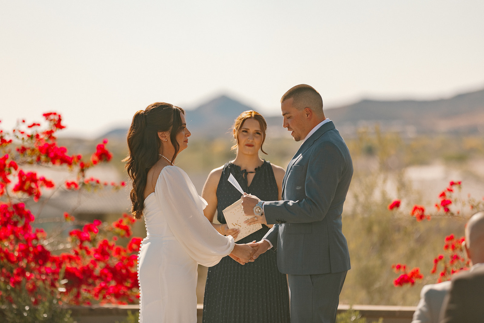 The groom reads his vows with heartfelt emotion during the ceremony at Blackstone Country Club, holding hands with the bride as the officiant looks on.
