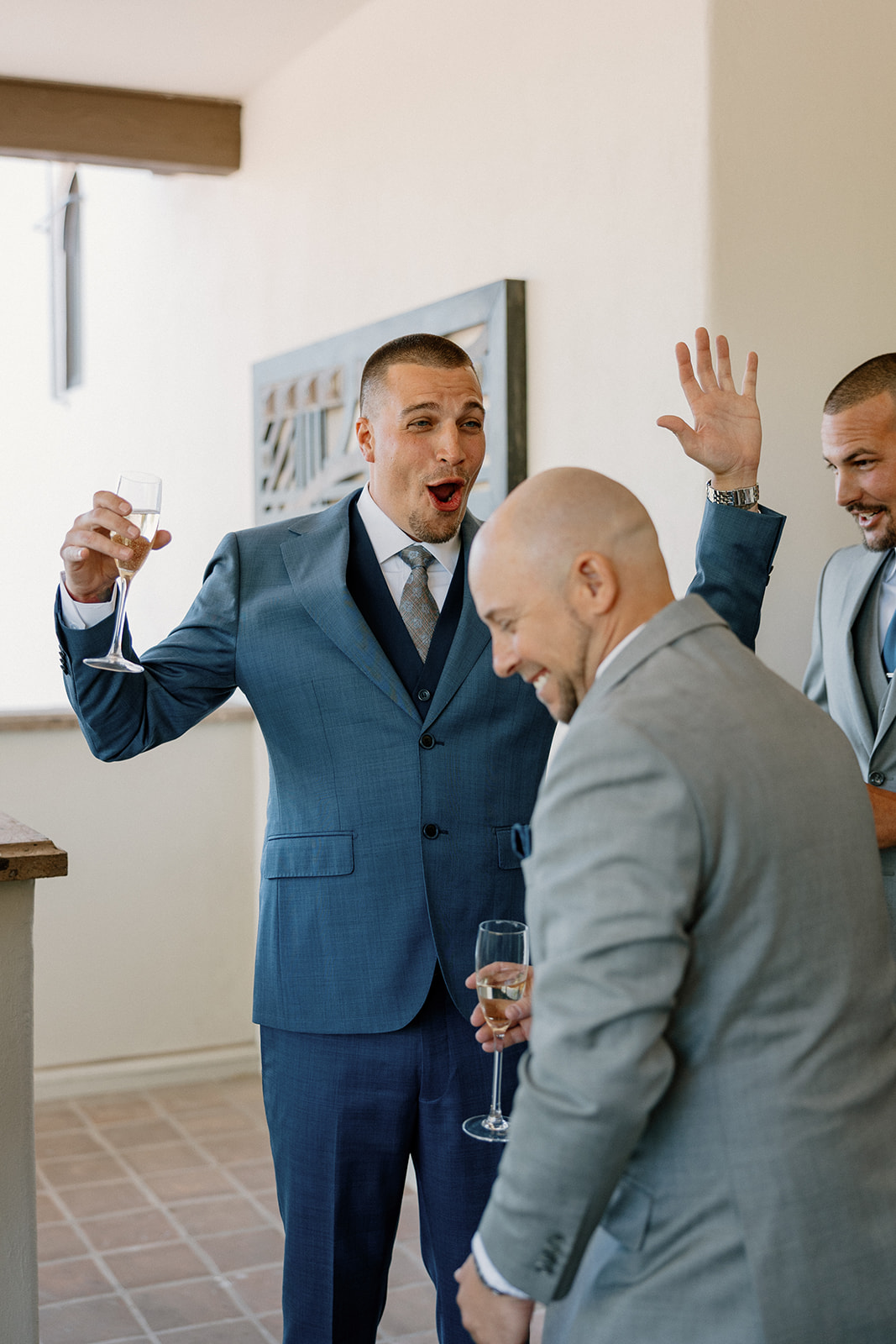 A burst of laughter between the groom and his groomsmen during pre-ceremony excitement on the shaded balcony.