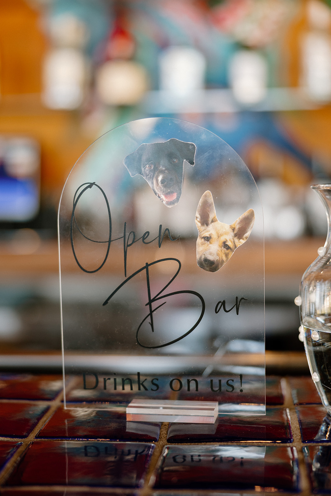 Clear acrylic bar sign featuring the couple’s dogs reads, “Open Bar – Drinks on us!” at Blackstone Country Club.