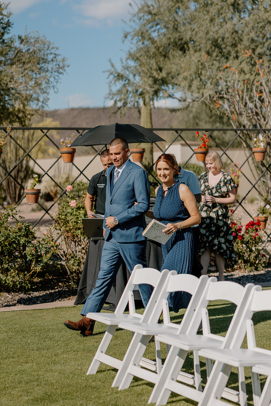 The groom walks in with the officiant, sharing a quick moment before the ceremony begins.