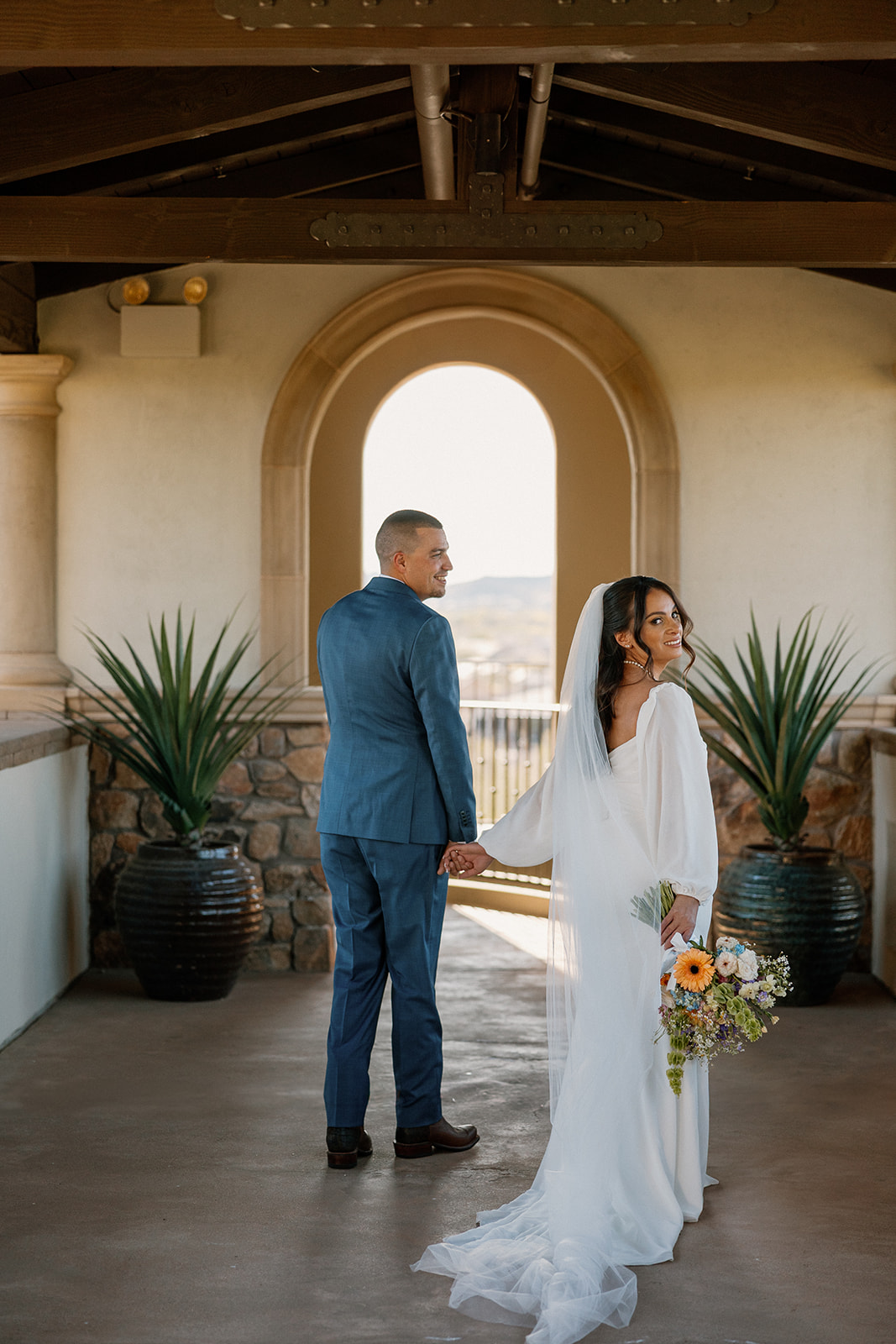 Bride and groom share a quiet moment under an arched breezeway at Blackstone Country Club, framed by soft morning light.