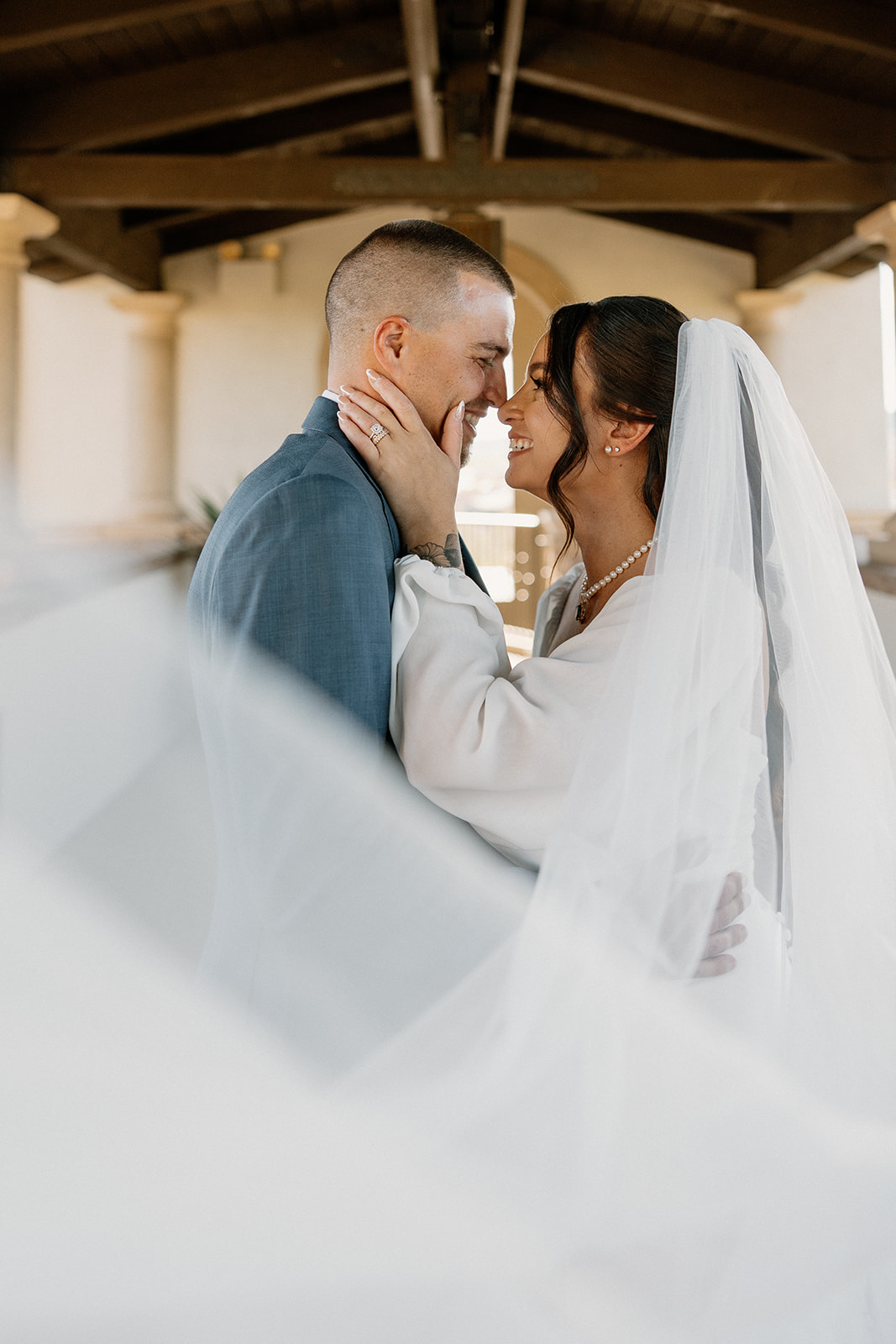 Bride and groom share an intimate moment beneath the covered walkway at Blackstone Country Club, the bride’s veil sweeping through the foreground.