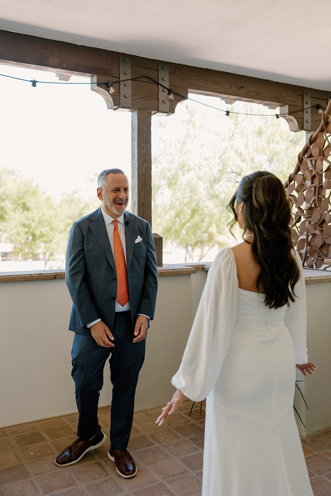 Dad reacts with joy and surprise during a first look moment with the bride, both beaming under the covered balcony at Blackstone Country Club.
