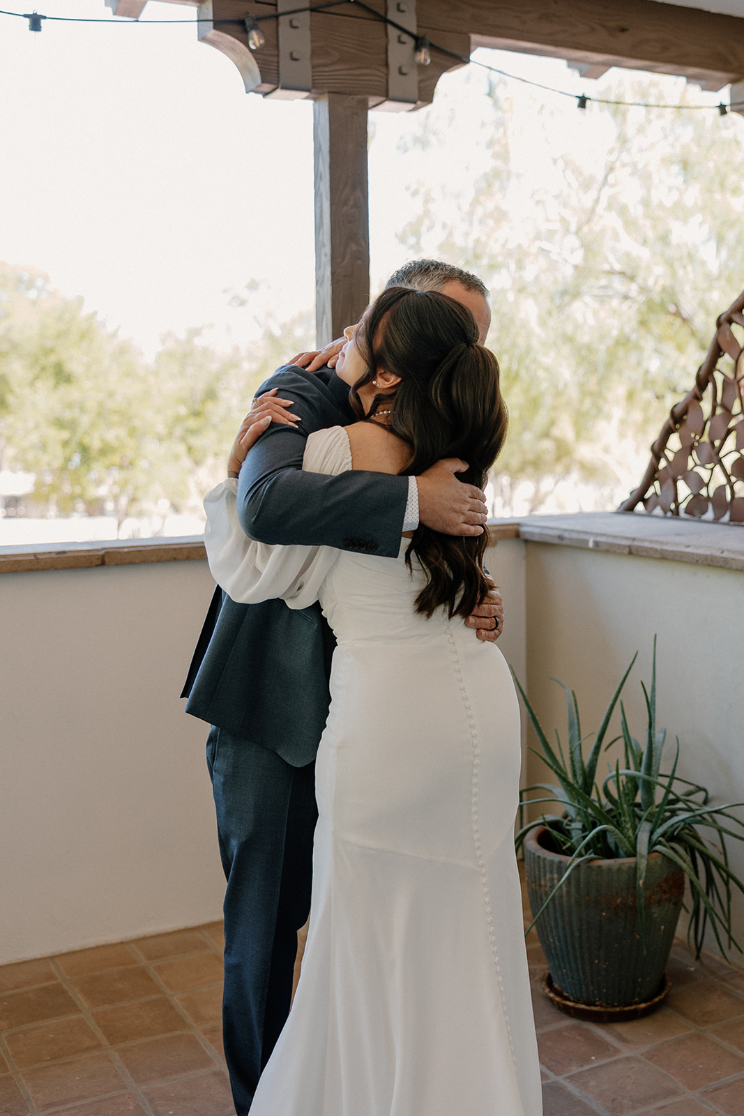 Emotional hug between bride and father before the ceremony, captured in a private moment on the shaded patio.