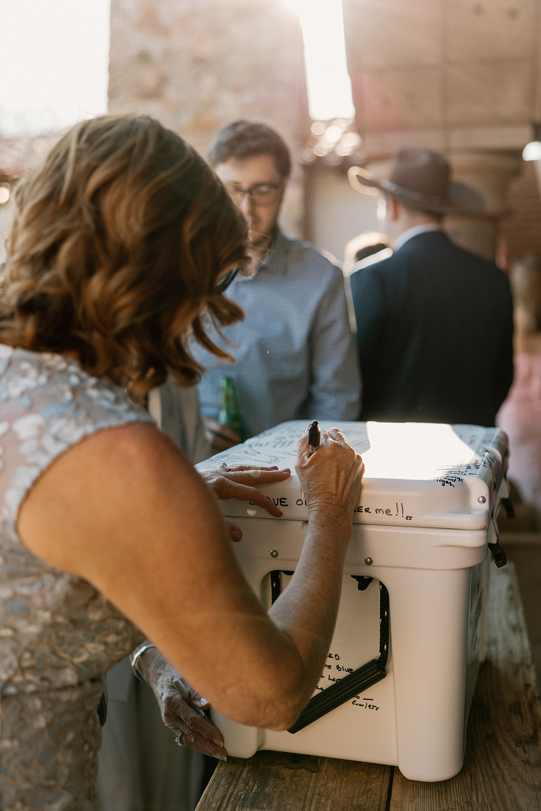 A guest adds their message to a Yeti cooler guestbook, a creative and personal twist on tradition.