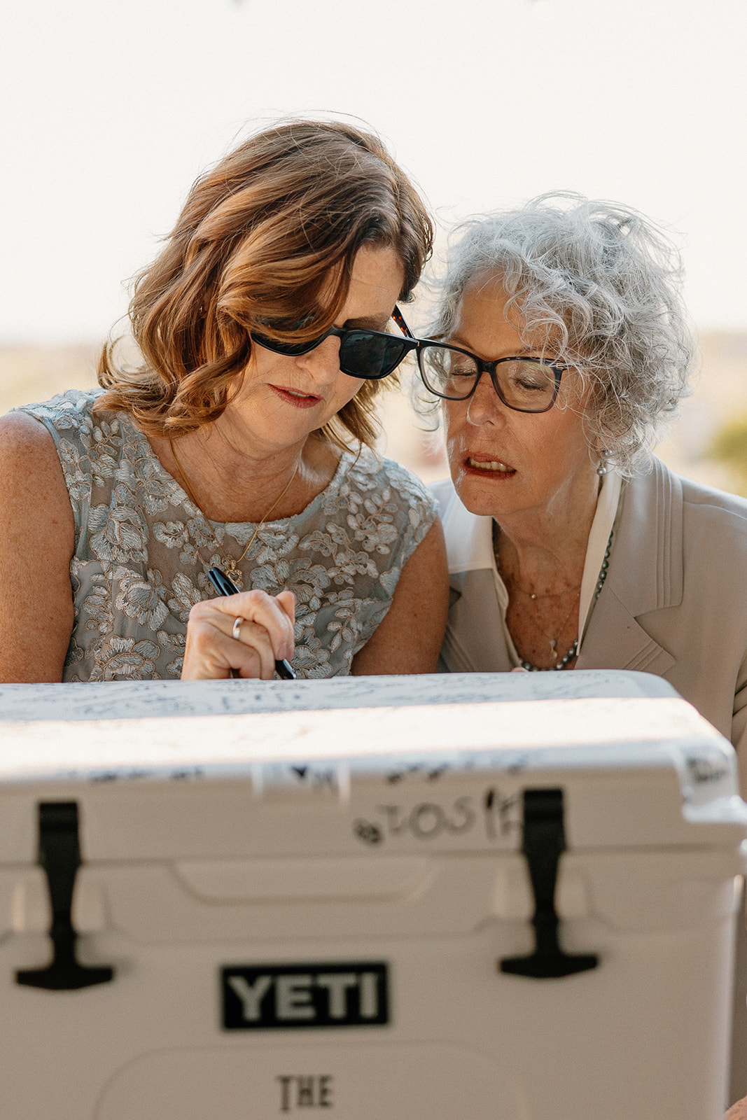 Two guests sign a white Yeti cooler as a creative guest book alternative at Blackstone Country Club.