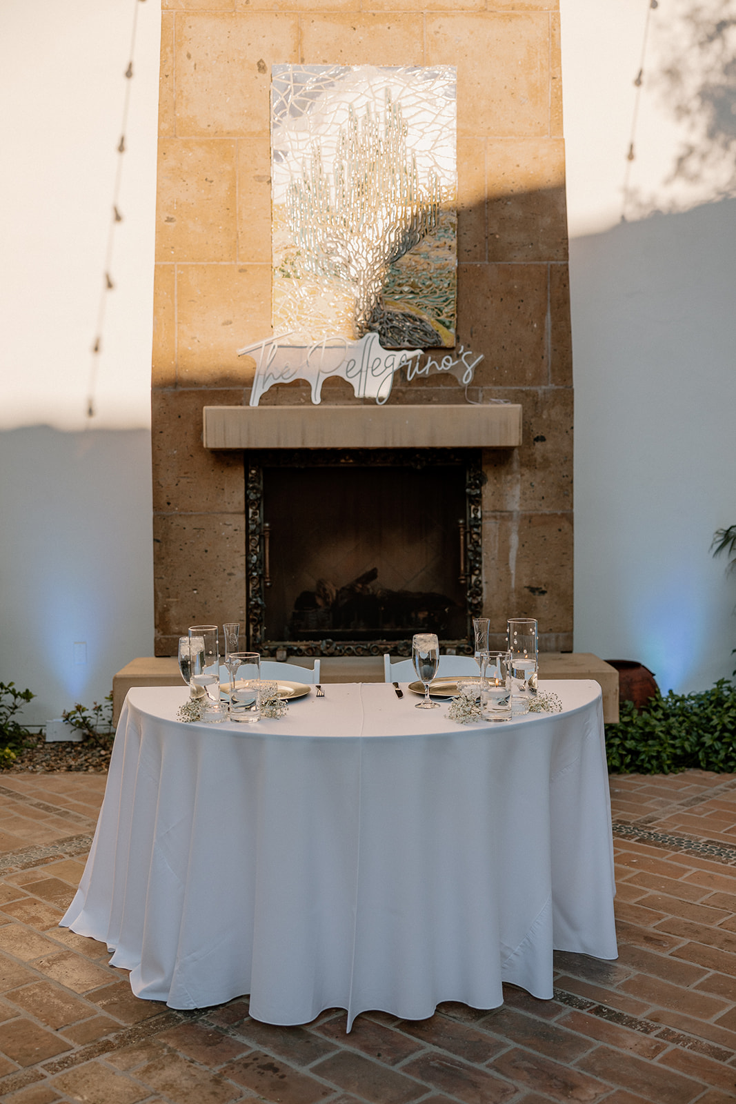 Elegant sweetheart table setup in front of a grand stone fireplace at Blackstone Country Club, glowing with late-afternoon light.