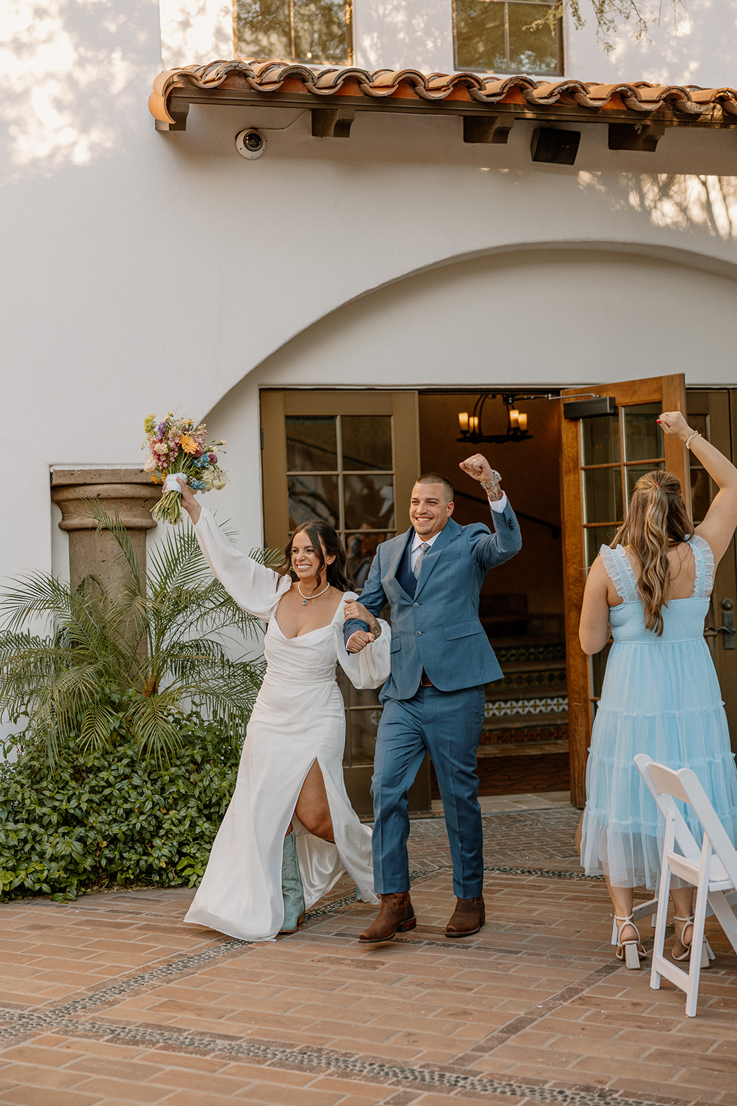 The newlyweds make their grand entrance to the reception at Blackstone Country Club, arms raised and all smiles.