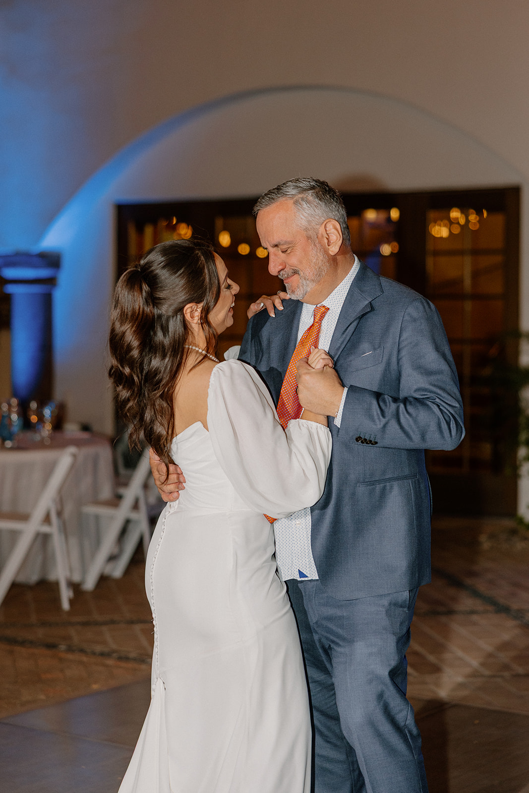 Father-daughter dance moment full of smiles and nostalgia, the bride resting her head close as they sway together.