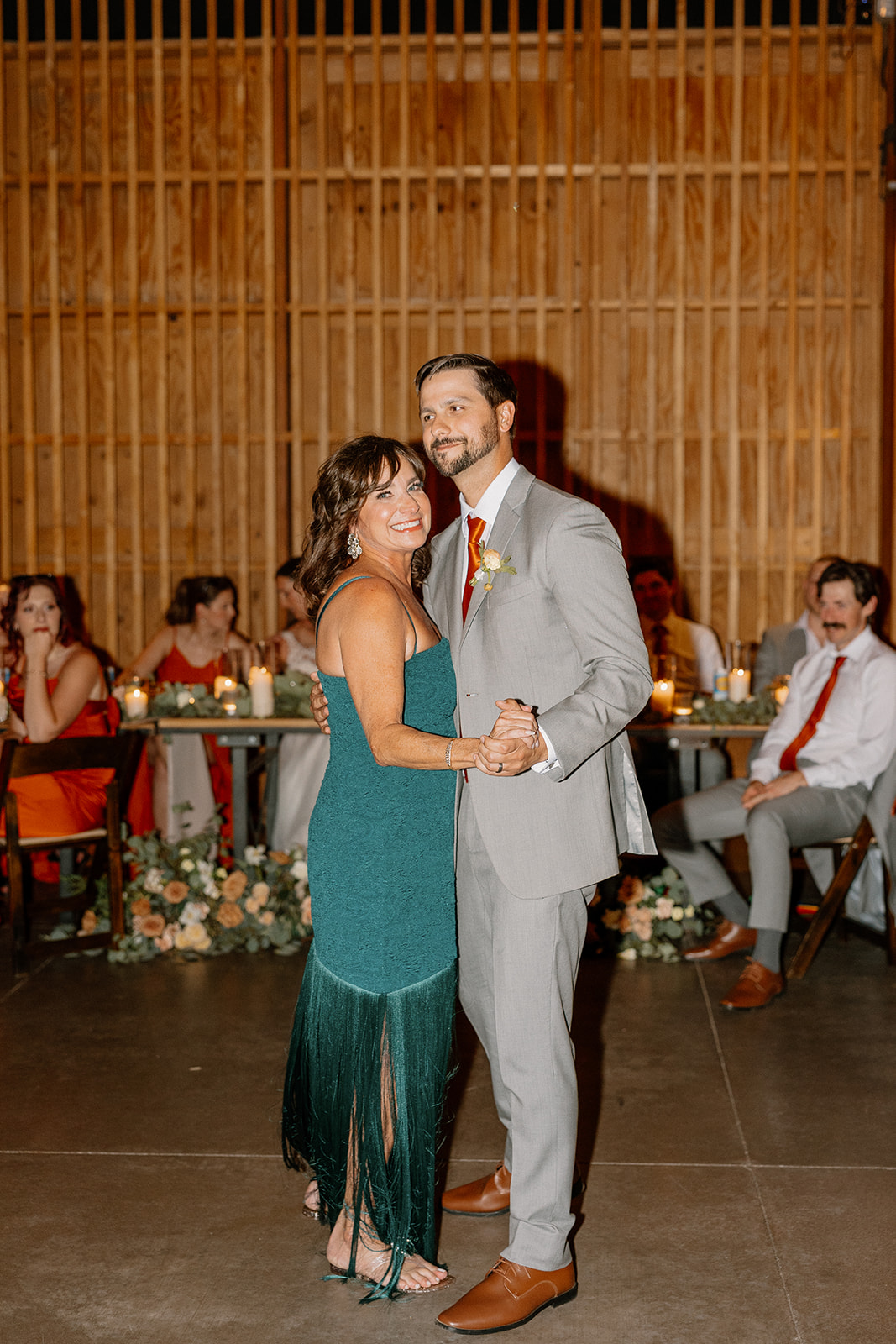 Groom dancing with his mom under the warm glow of the reception lights.