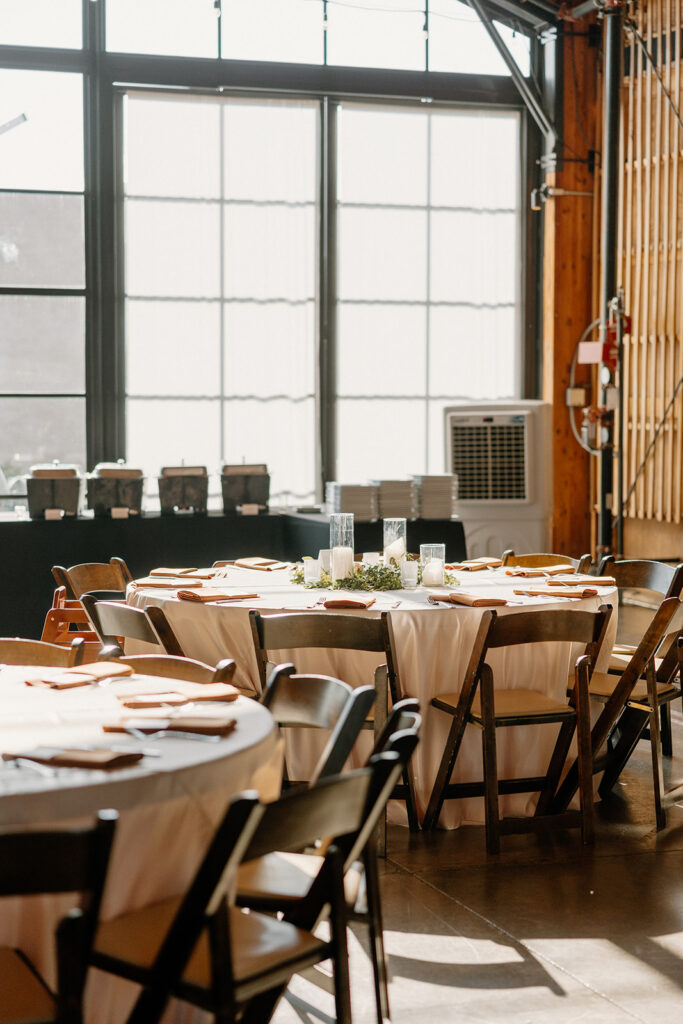 Reception tables at The Paseo set with white linens and terracotta accents, sunlight pouring through the windows.
