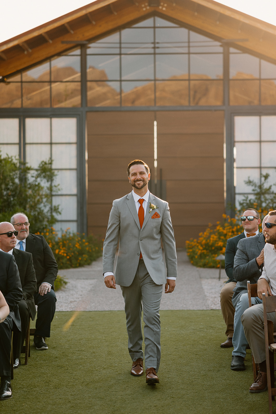 Groom walking down the aisle at The Paseo with a big smile and sunshine pouring in through the ceremony space.