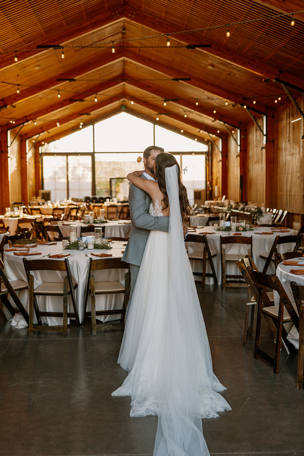 Bride and groom embracing in the reception hall surrounded by elegant table settings and soft lighting at The Paseo.