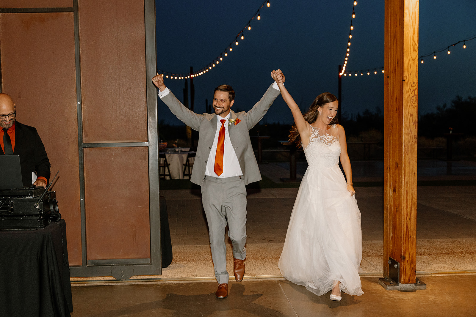 Bride and groom making their grand entrance into the reception with hands raised and huge grins.