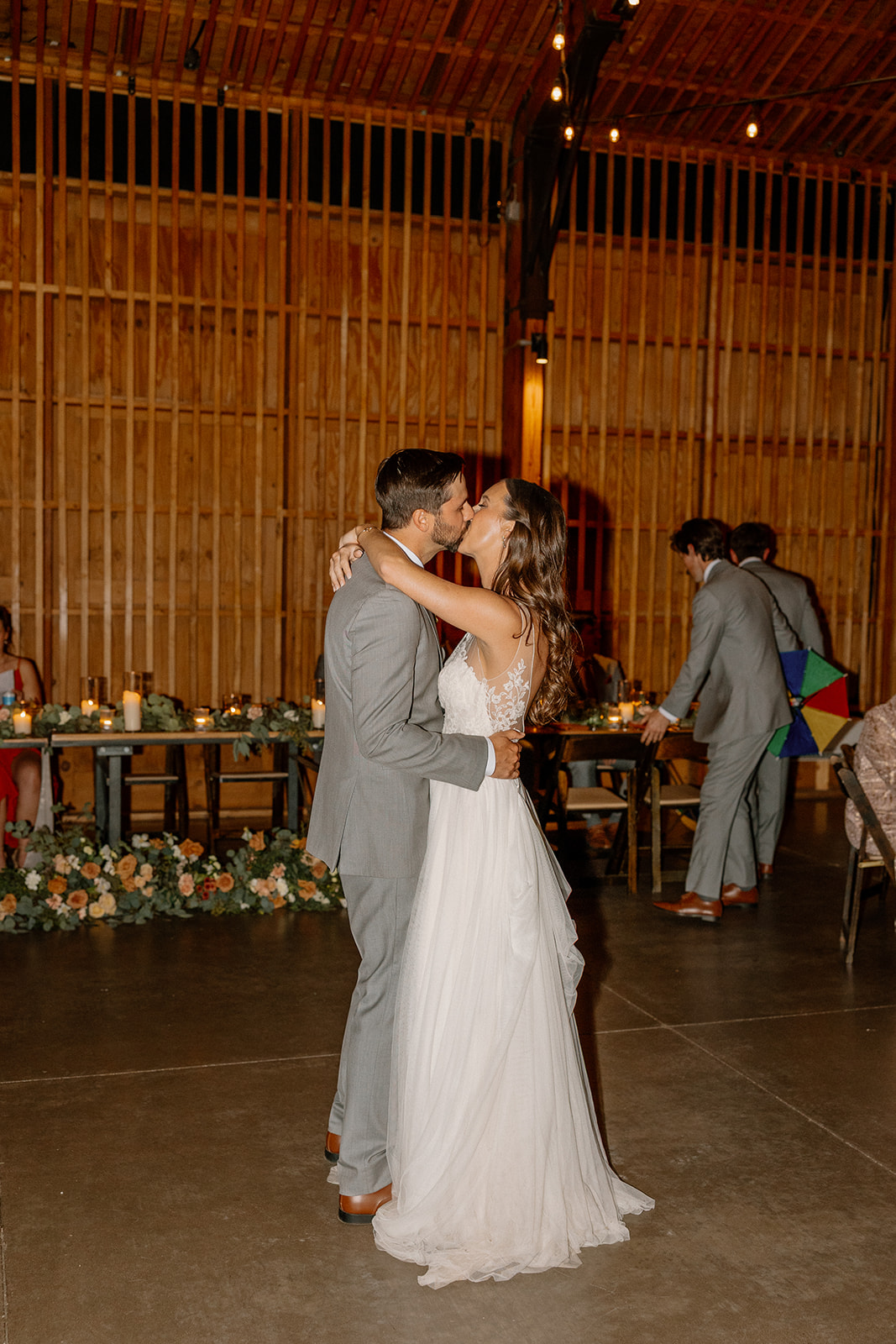 First dance under warm ambient lighting inside the modern-rustic reception hall.