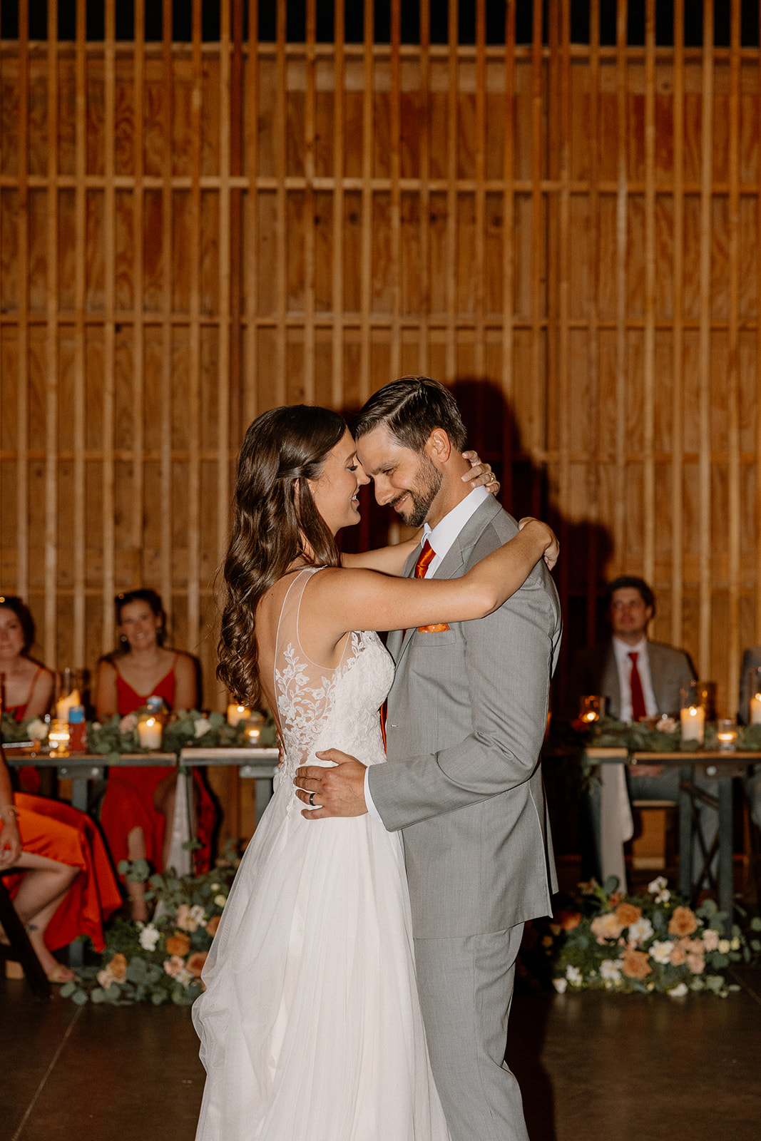 Bride and groom sharing their first dance, forehead to forehead, surrounded by candlelight.