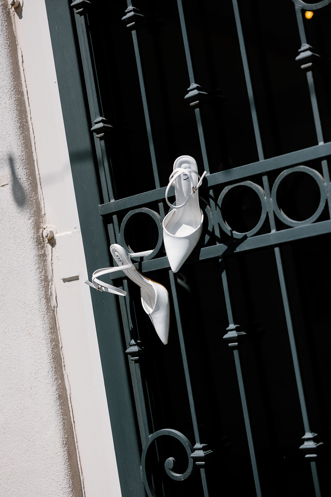 Elegant white bridal heels displayed on a dark metal gate outside SoHo63 in Chandler, Arizona.