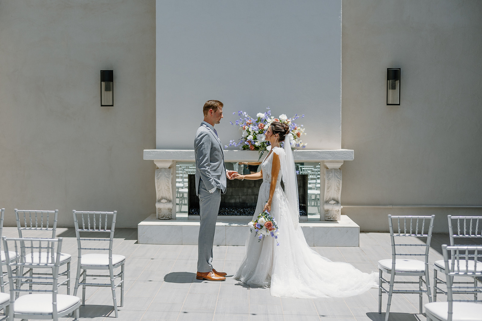 Bride and groom hold hands in front of the fireplace during an intimate vow moment at Arizona wedding venue