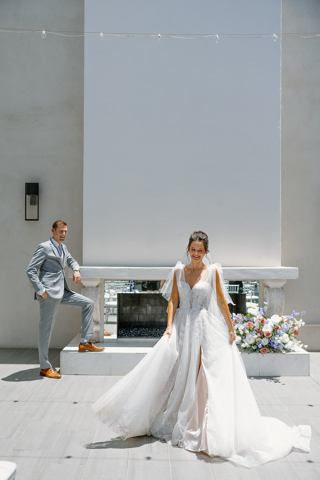 Bride and groom posing confidently by the SoHo63 outdoor fireplace with pastel floral arrangements.