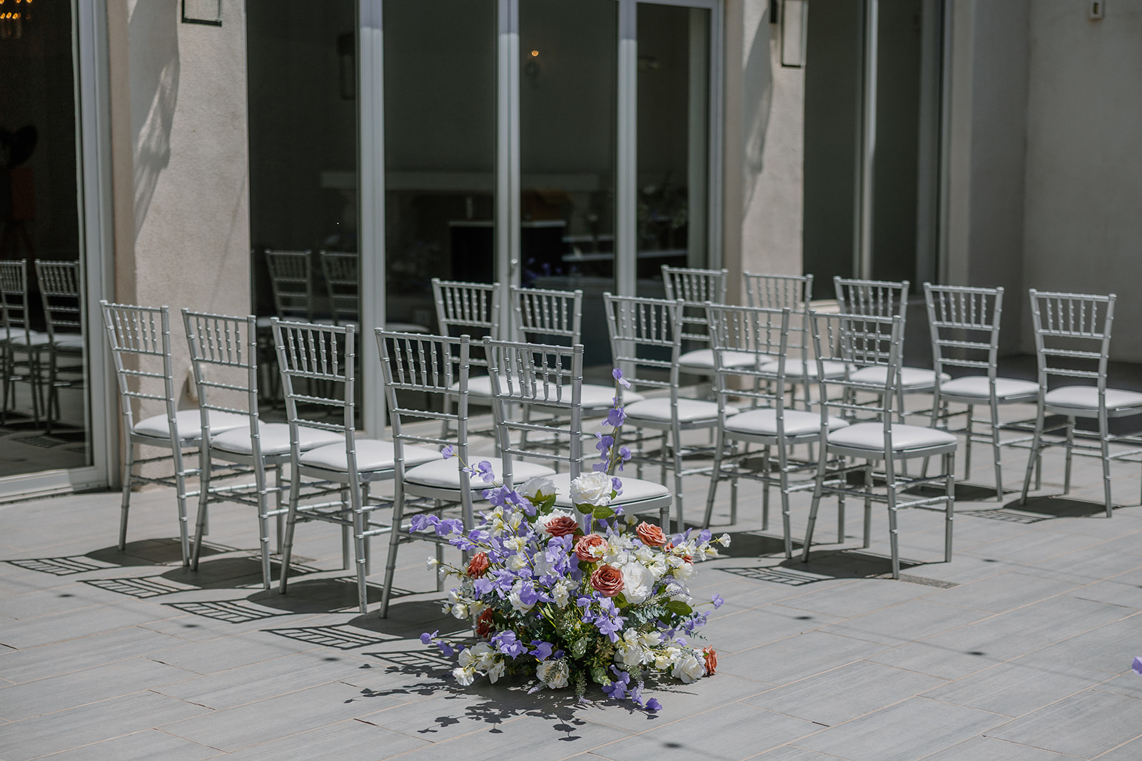 Ceremony setup at SoHo63 with white chiavari chairs and pastel floral aisle arrangements on the terrace.
