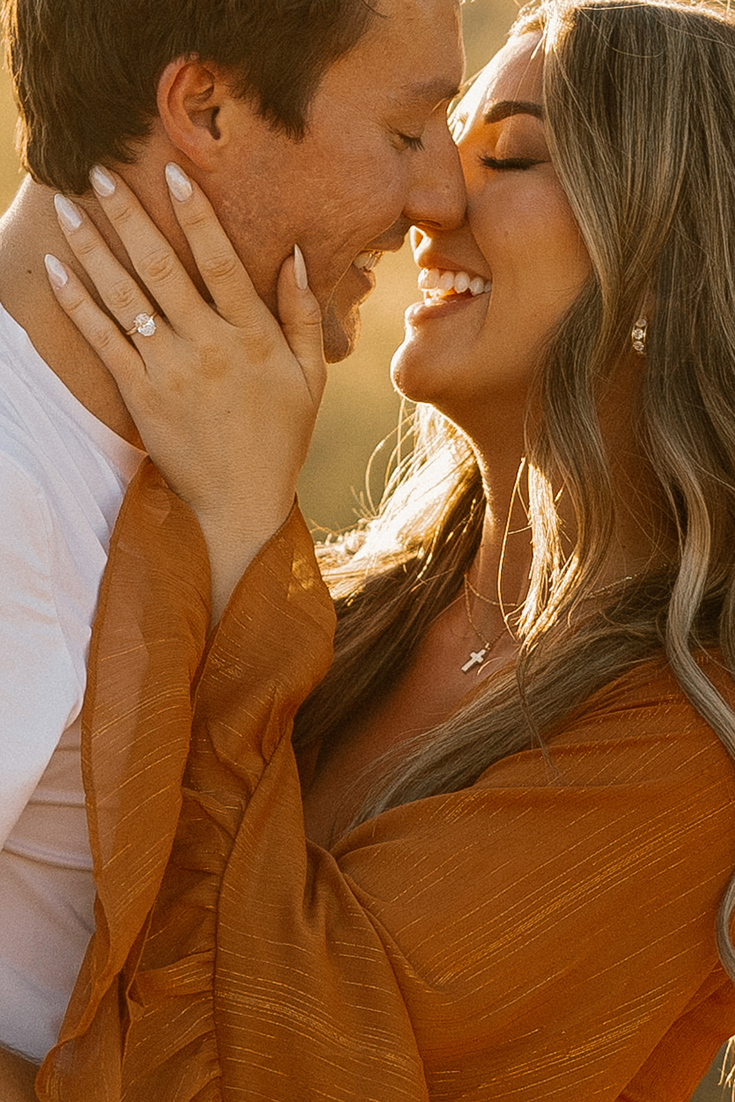 Close-up shot of a couple smiling with noses touching, showcasing her engagement ring and radiant joy.