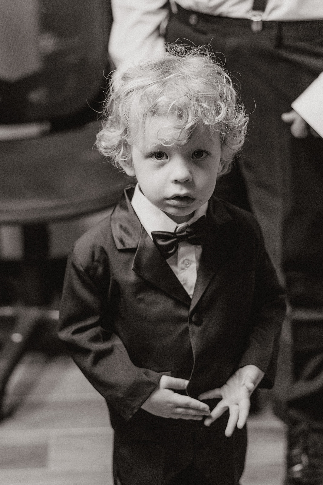 A black-and-white portrait of the ring bearer in his tiny suit, caught mid-expression.