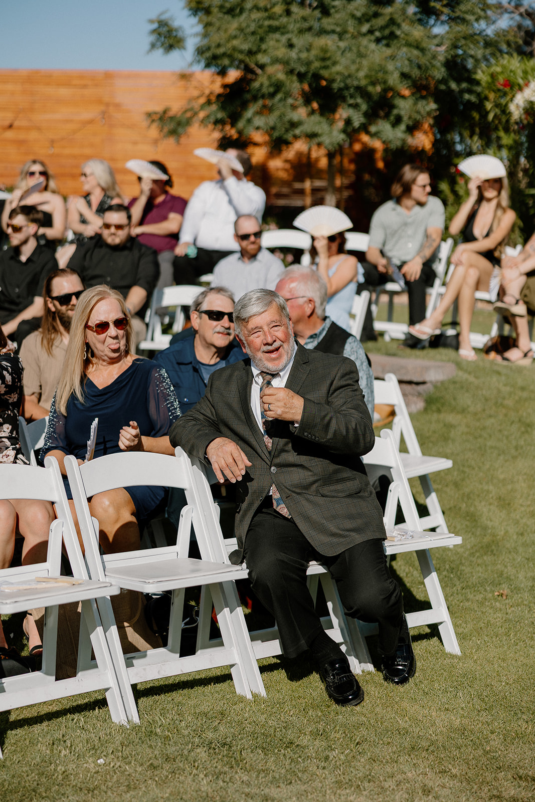 Guests gather outdoors, laughing and chatting before the ceremony begins.