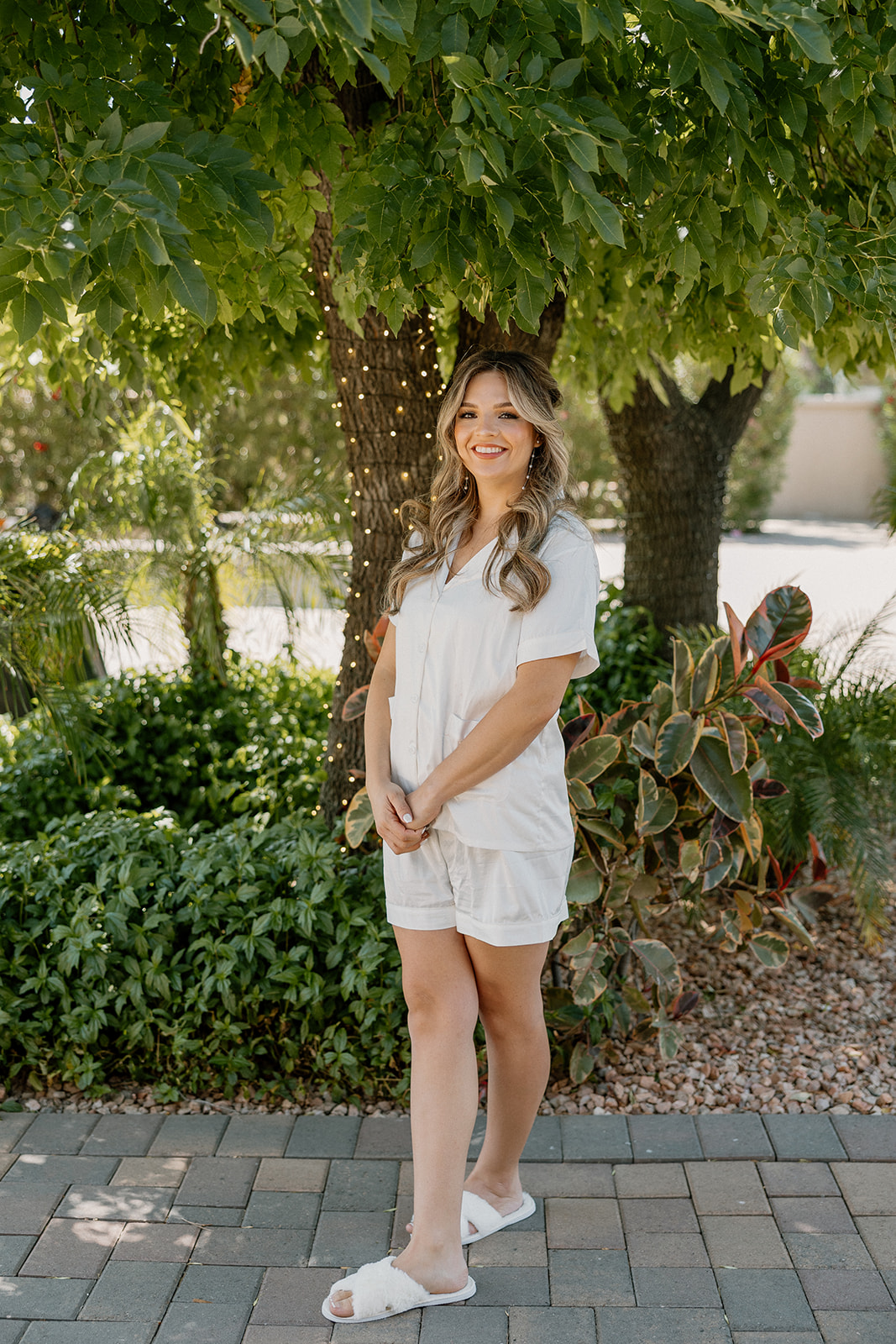 The bride stands confidently on a brick path, glowing with morning light and pre-ceremony excitement at an Arizona wedding venue.