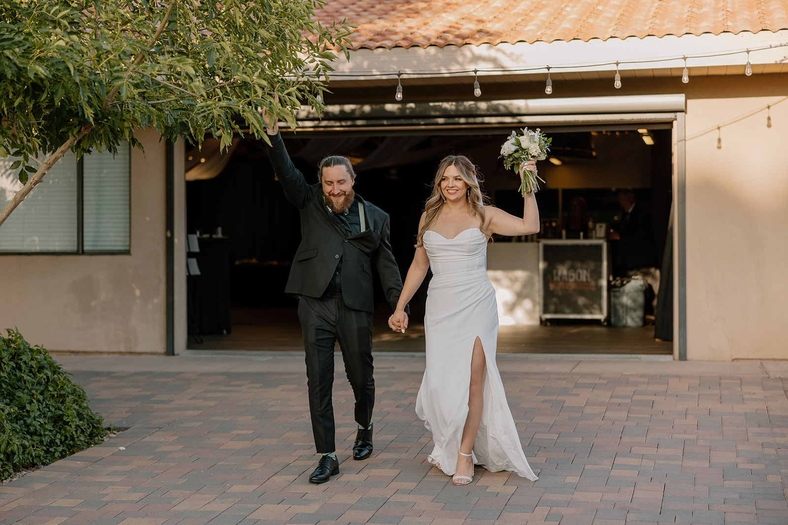 Just-married energy! The couple makes their grand entrance, hands held high, beaming with excitement.