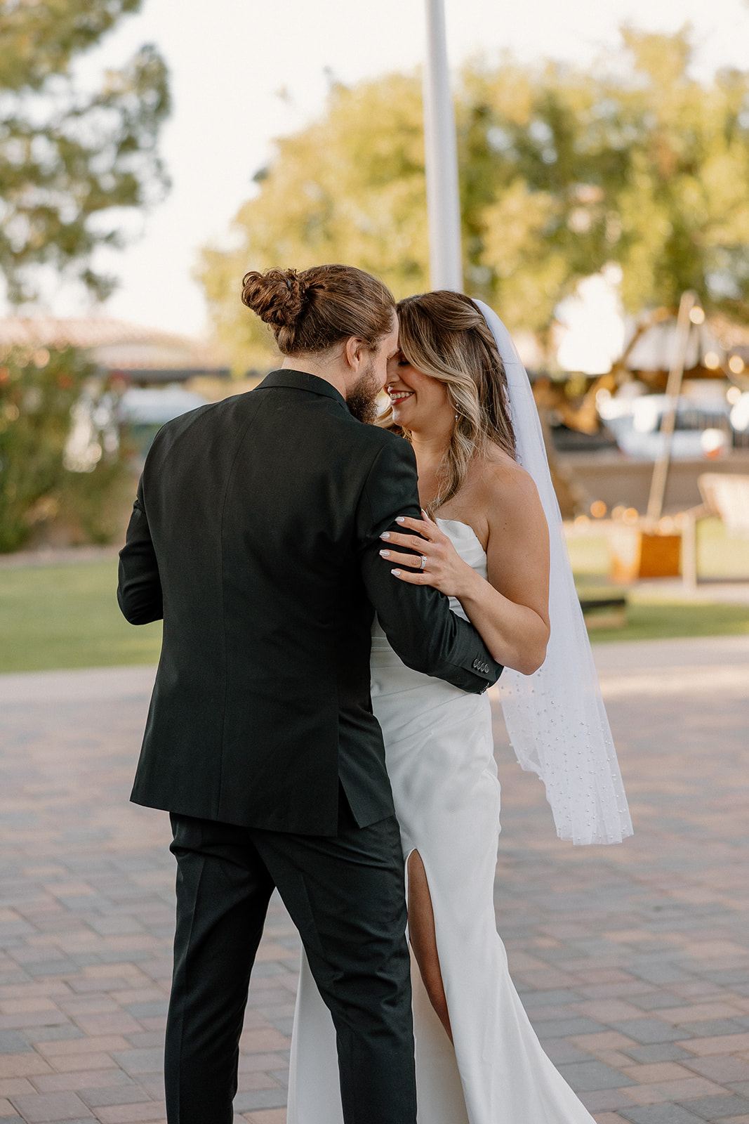 The couple shares a quiet first dance under soft light, smiling and leaning into each other at their Arizona wedding venue.