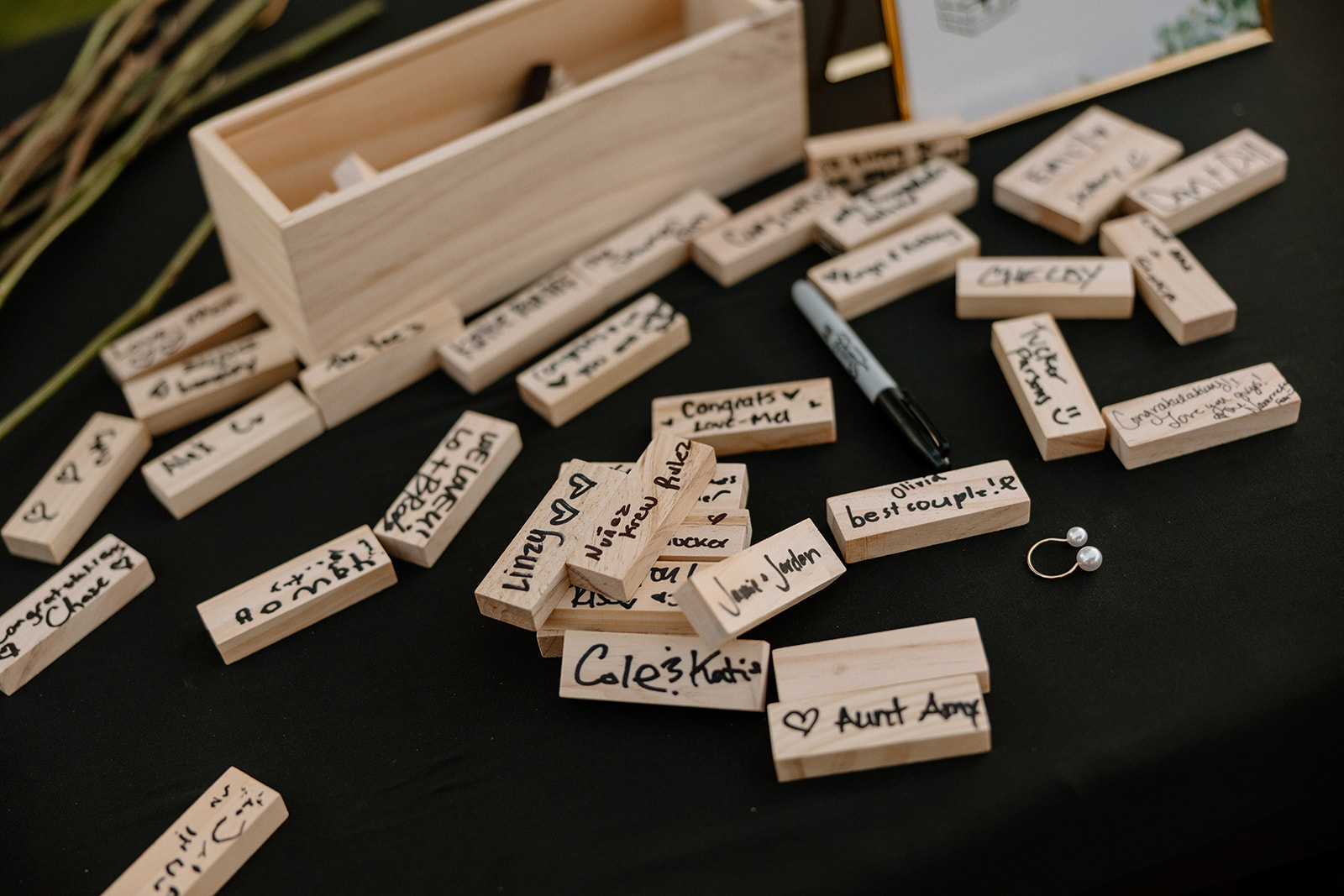 Jenga pieces are covered in handwritten notes and signatures—guests leave playful and heartfelt messages for the couple.