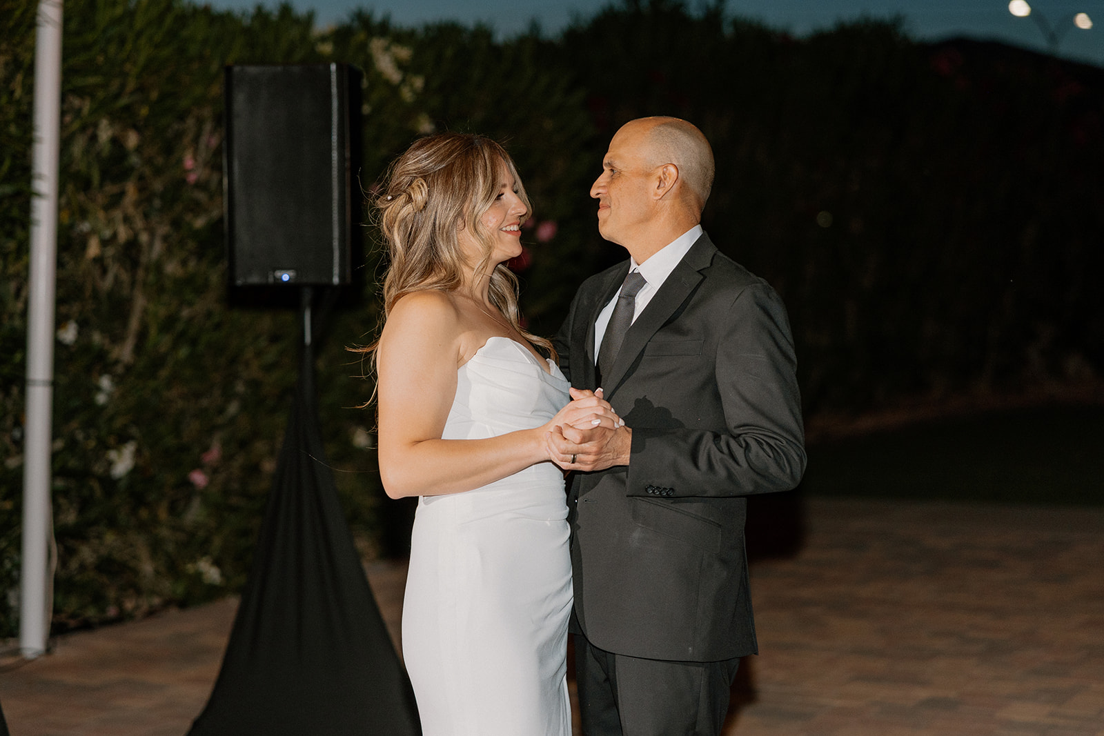 The bride shares an emotional father-daughter dance as twilight settles in.