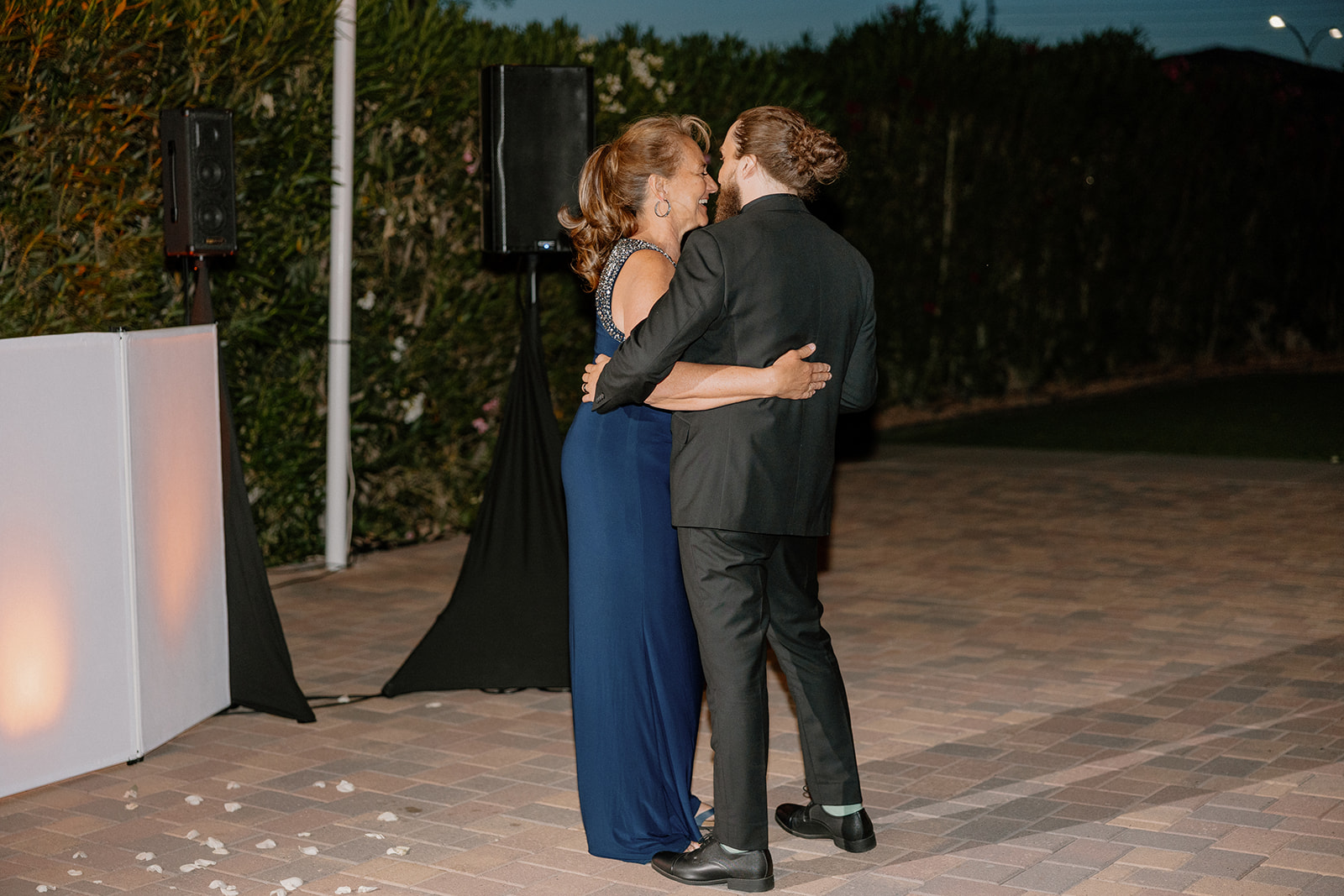A sweet mother-son dance unfolds under the evening sky on the outdoor dance floor of their Arizona wedding venue.