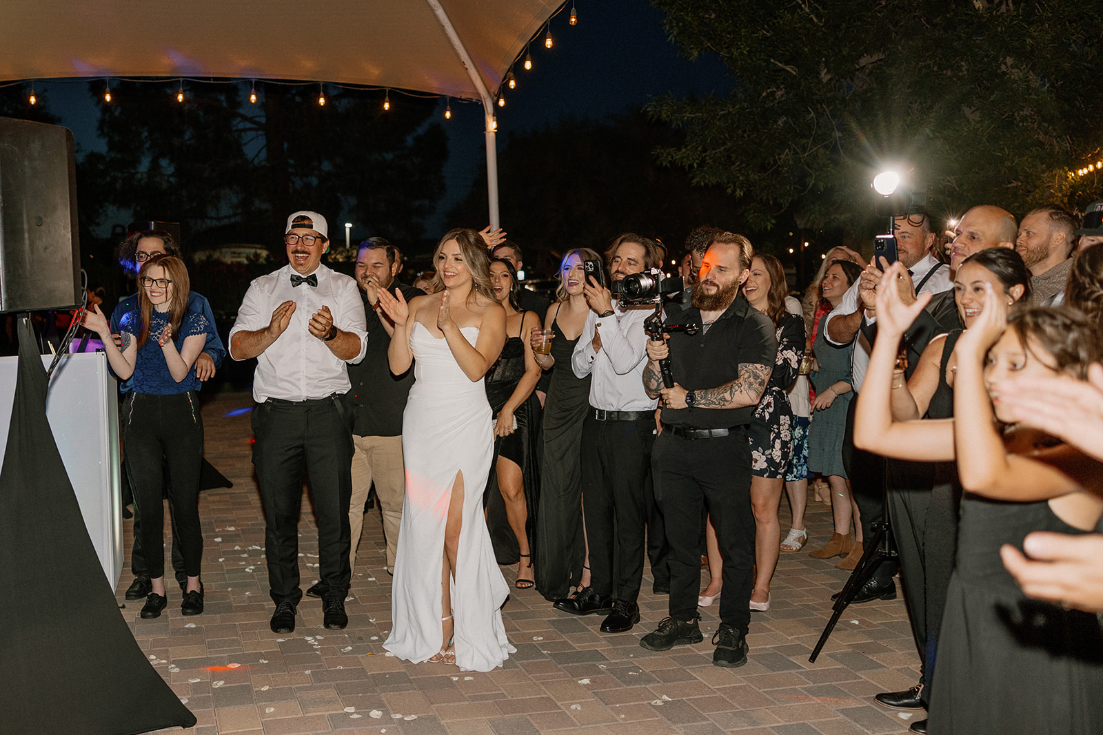 Guests and vendors surround the bride on the dance floor, cheering her on during a big moment at the reception.
